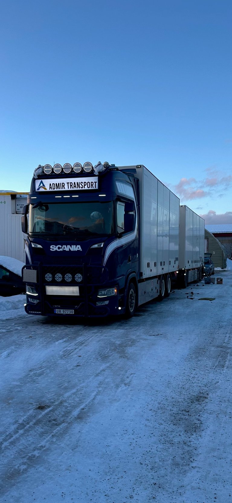 Svart Scania lastebil med Admir Transport merking parkert på snø